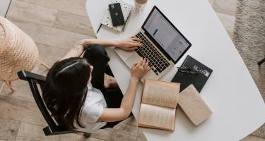 Woman in bright room sitting at laptop on desk