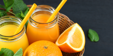 orange juice with straws and oranges in a basket