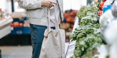 Man carrying fabric tote bag in vegetable aisle of a supermarket