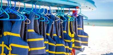 Blue and yellow life jackets hanging on a railing on a beach