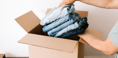 Hands placing folded clothes into cardboard box