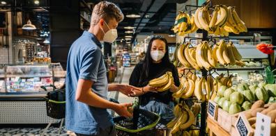 Man and woman in face masks shopping for bananas.