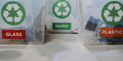 Des boîtes de recyclage du verre, du papier et du plastique avec les matériaux correspondants à l'intérieur.
