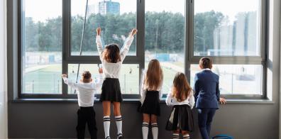 Kids in school uniform looking out a window.